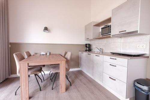 una pequeña cocina con mesa de madera y sillas en Erve Fakkert, en Rossum