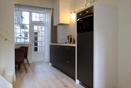 a kitchen with a black refrigerator and a table at Huisje aan de gracht in Franeker