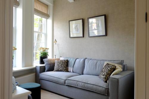 a living room with a blue couch with pillows on it at Huisje aan de gracht in Franeker