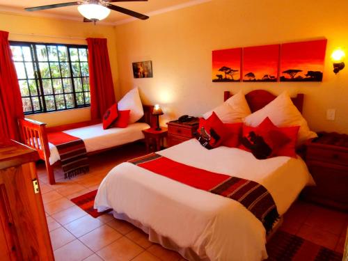 una habitación de hotel con dos camas y un sofá en African Footprints Lodge, en Midrand