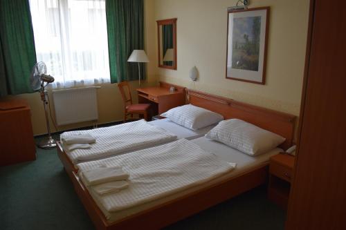 a hotel room with two beds and a desk at Paprika Panzió in Hegyeshalom