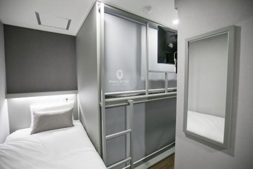 a small room with a bed and a mirror at Philstay Myeongdong Station in Seoul