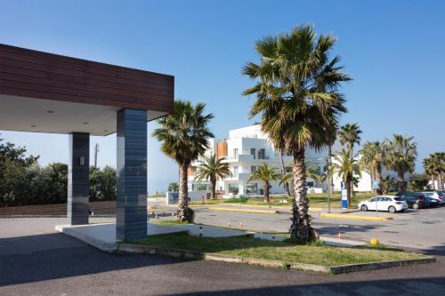 a parking lot with palm trees in front of a building at Elite City Resort in Kalamata