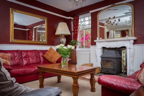 a living room with a red couch and a fireplace at Stanley House in Eskdale