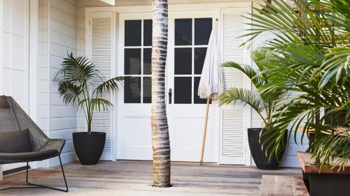 a porch with palm trees and a white door at 28 Degrees Byron Bay - Adults Only in Byron Bay
