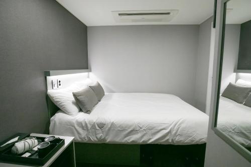 a small room with a bed and a mirror at Philstay Myeongdong Station in Seoul