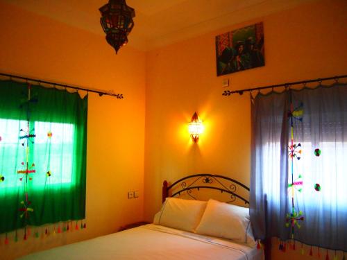 a bedroom with a bed and two windows with curtains at Riad Al Anwar in Tinerhir
