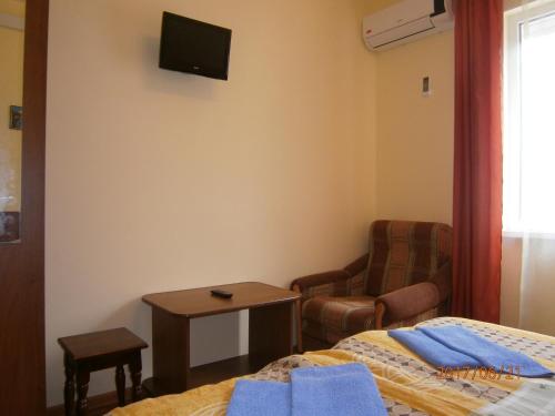 a bedroom with a bed and a chair and a tv at Guest house Barhatniy sezon in Novy Afon