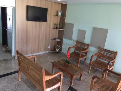a room with three benches and a tv on a wall at Caçula Palace Hotel in Catalão
