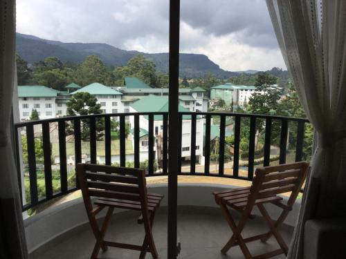 due sedie su un balcone con vista sulla città di Skylight Apartment a Nuwara Eliya