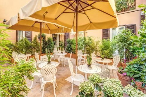 a patio with tables and chairs and umbrellas at Charme Spagna Boutique Hotel in Rome