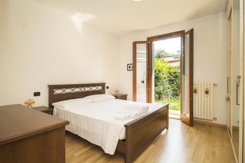 サロにある"Il Parco" bilocale con giardinoのベッドルーム1室(ベッド1台付)、スライド式ガラスドアが備わります。