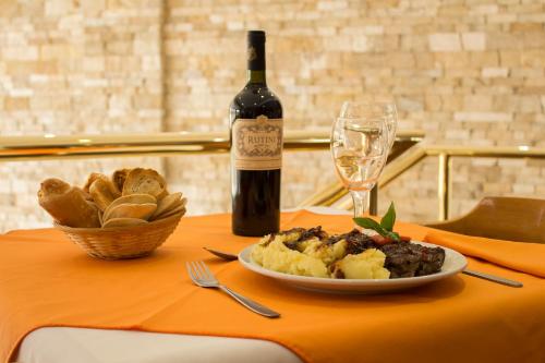 a table with a plate of food and a bottle of wine at Hotel Dior in Tandil
