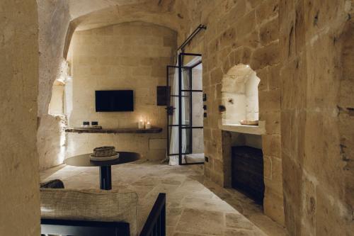 una camera con tavolo in una parete in pietra di Palazzotto Residence&Winery a Matera