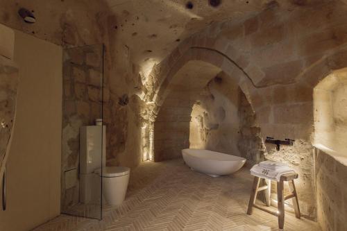a bathroom with a tub and a sink in a cave at Il Palazzotto I Residence & Winery in Matera