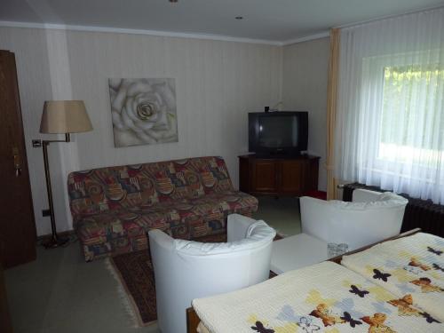 a hotel room with two beds and a couch at Hotel Heidehaus in Mönchengladbach