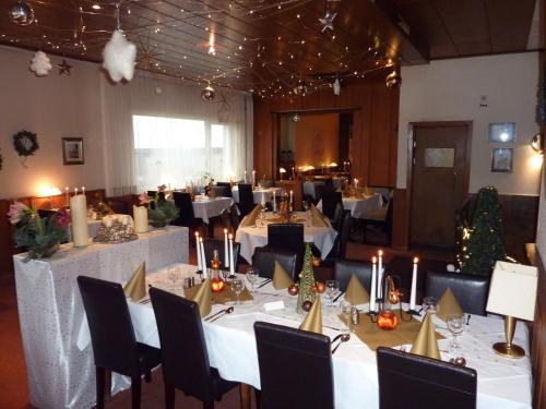 a dining room with white tables and chairs and christmas trees at Hotel Heidehaus in Mönchengladbach
