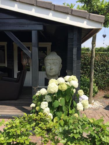 a statue of a head on a porch with flowers at Hof van donzel in Nistelrode