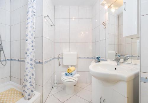 a white bathroom with a toilet and a sink at Apartments Jurić in Podstrana