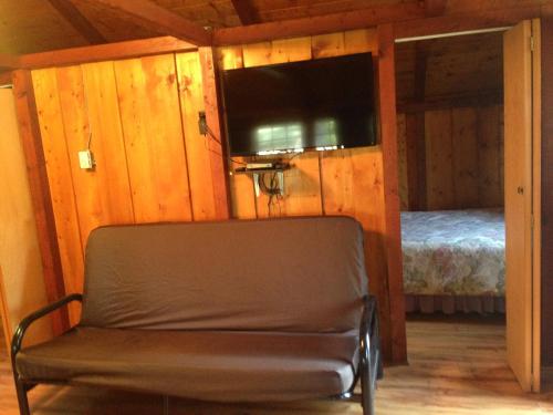 a chair in a room with a tv and a bed at Addison's Bungalows in Brisco