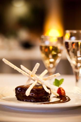 un morceau de nourriture sur une assiette sur une table avec des verres à vin dans l'établissement Logis Hôtel & Restaurant Arcombelle, à Val-de-Meuse