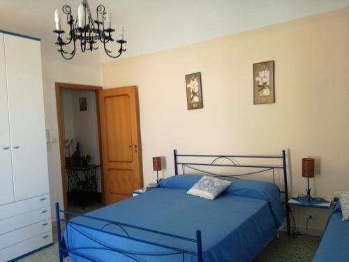 ein Schlafzimmer mit einem blauen Bett und einem Kronleuchter in der Unterkunft Sotto L'Arco in Santo Stefano di Camastra