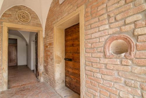 an empty hallway with a brick wall and a wooden door at Hotel Casa a Colori Venezia in Dolo