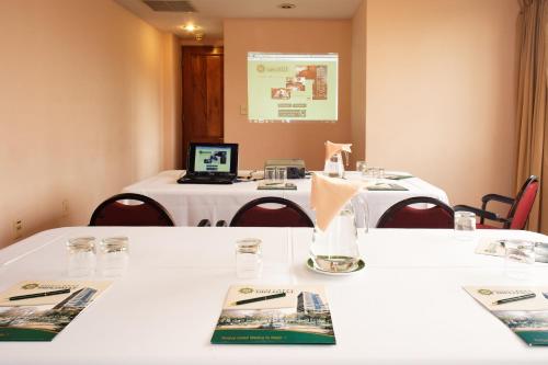 a meeting room with white tables and a laptop on top at Hotel Diplomat in Cochabamba