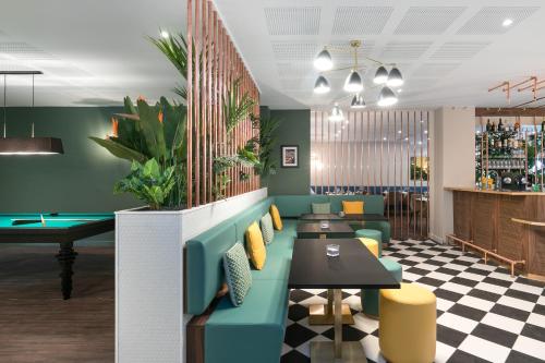 a restaurant with a blue couch and a pool table at Hôtel Birdy by Happyculture in Aix-en-Provence