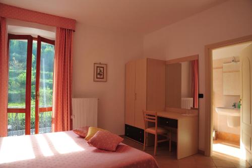 a bedroom with a bed and a desk and a window at Affittacamere B&B Trattoria della Posta in Maissana