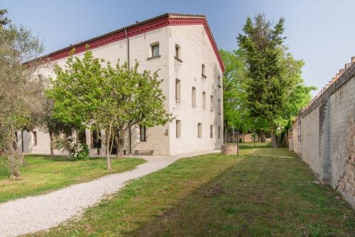 an old white building with trees in front of it at Hotel Casa a Colori Venezia in Dolo
