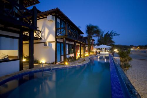 a swimming pool in front of a building at night at Chez Pitu Praia Hotel in Búzios