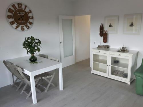 a white table and chair in a room with a clock at apartament Sant Pere in Sant Pere Pescador