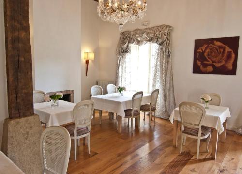 een eetkamer met witte tafels en stoelen en een kroonluchter bij Posada Villa Esperanza in Liérganes