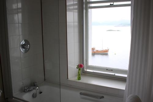 eine Dusche mit einem Fenster und eine Vase mit einer Blume in der Unterkunft Crinan Hotel in Crinan