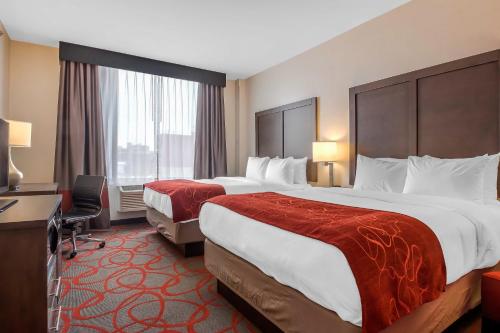 a hotel room with two beds and a desk at Comfort Inn & Suites near Stadium in Bronx