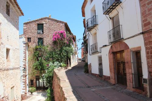 an alley in an old town with pink flowers at Ca Felicitat in Vilafames
