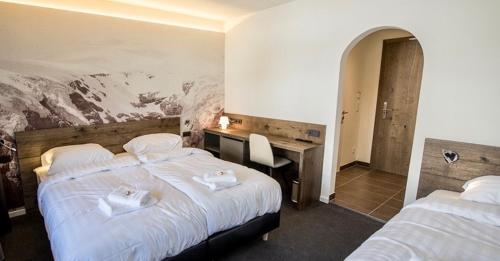 Pokój hotelowy z 2 łóżkami i biurkiem w obiekcie Marmotta Alpin hotel w mieście Mühlbach am Hochkönig