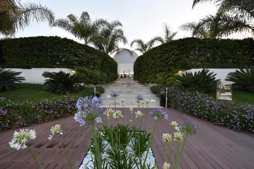 a walkway in a garden with flowers and trees at Hotel Royal Paestum in Paestum