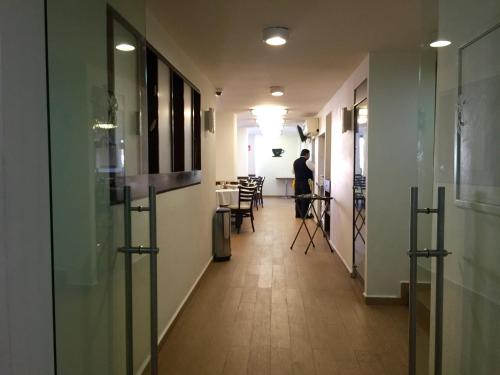 a man standing in a hallway with a table and chairs at Hotel Castropol in Mexico City
