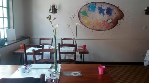 ein Esszimmer mit einem Tisch und Stühlen sowie einem Gemälde an der Wand in der Unterkunft Auberge de l'Arc en Ciel in Fauquembergues