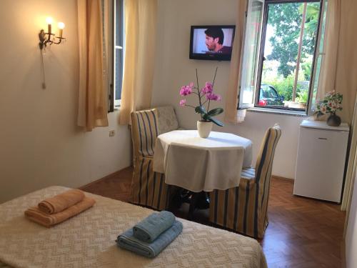 a room with a table and a vase with flowers on it at Rooms Tusculum in Opatija