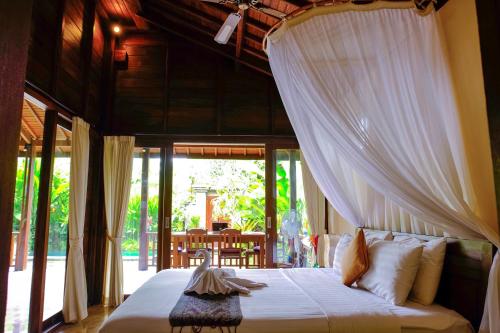 una camera con un letto a baldacchino bianco di Prama House ad Ubud