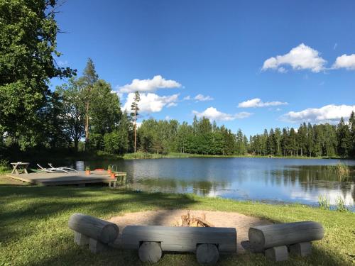 a lake with a boat and a bench in the grass at Dzirnavkalns in Cesvaine