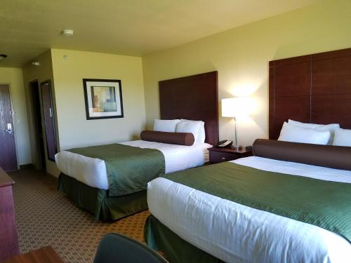 a hotel room with two beds and a desk at Cobblestone Inn & Suites - Bottineau in Bottineau