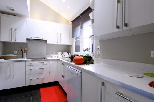 a kitchen with white cabinets and an orange on the counter at Comme une parenthèse au coeur des hortillonnages in Amiens
