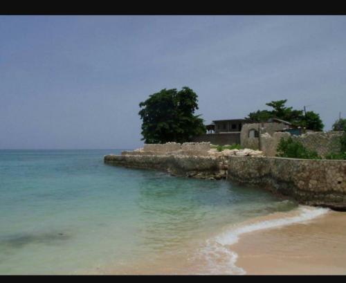 a beach with a stone wall and the ocean at Shades Cottage Guesthouse in Blue Hole