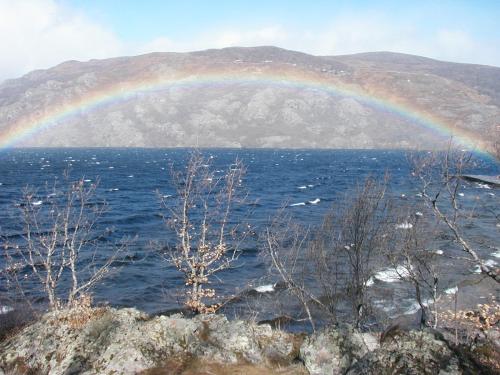 a rainbow over a body of water with a mountain at Hostal Carmen in El Puente