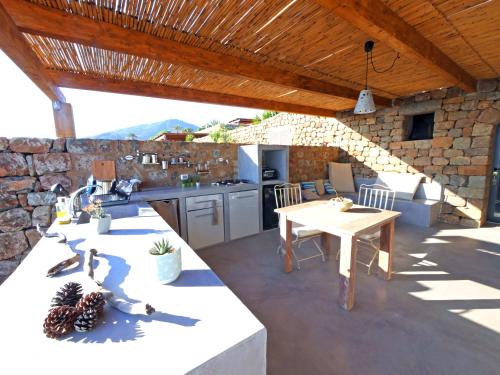 un patio con tavolo, una cucina e un muro in pietra di TGI Dammusi Preziosi a Pantelleria