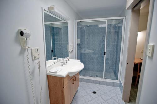biała łazienka z umywalką i prysznicem w obiekcie Centrepoint Motor Inn w mieście Rockhampton